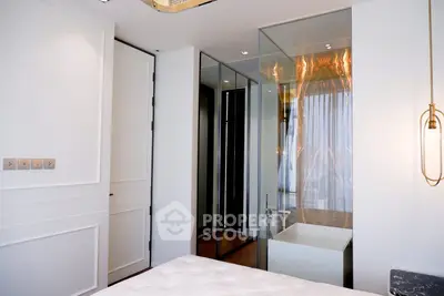 Luxurious bedroom with modern glass-enclosed bathtub and elegant lighting.