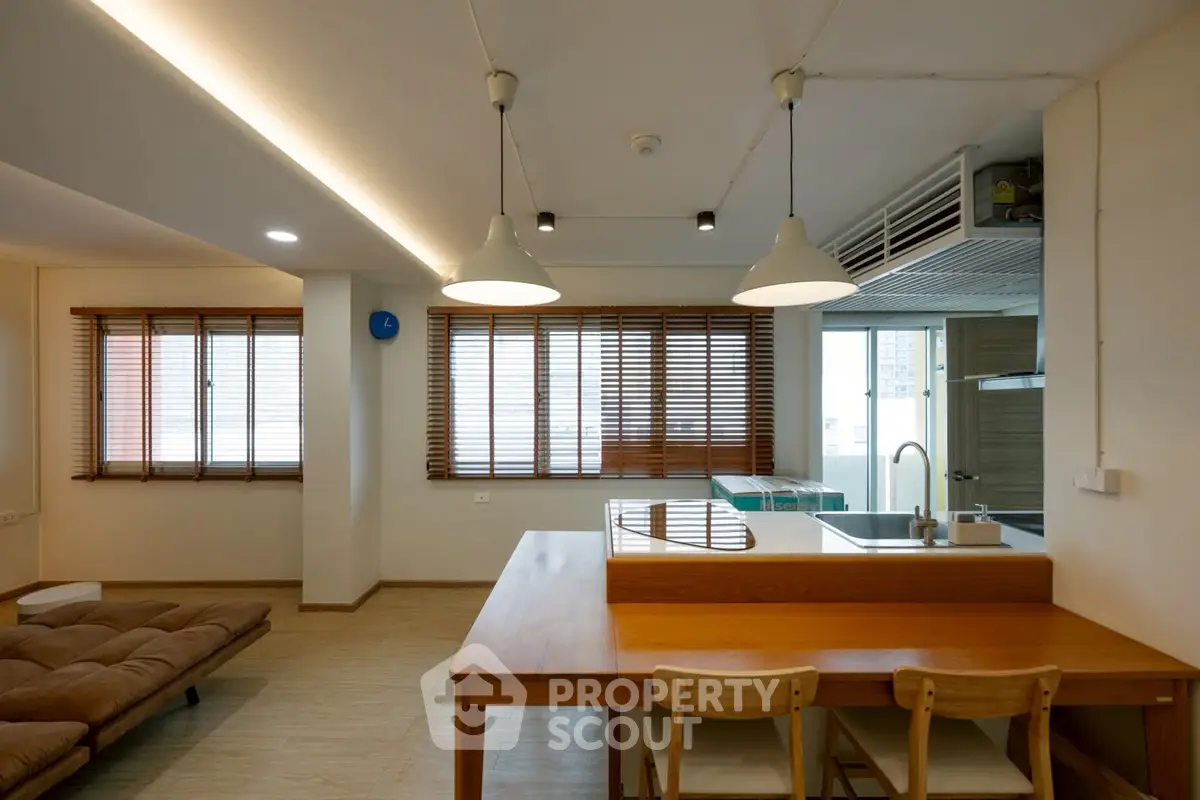 Modern open-plan living area with wooden dining table and cozy seating.