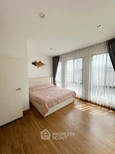 Spacious bedroom with large windows and elegant wooden flooring