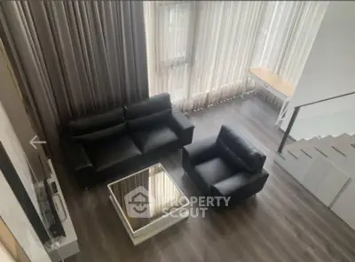 Modern living room with sleek black furniture and large windows