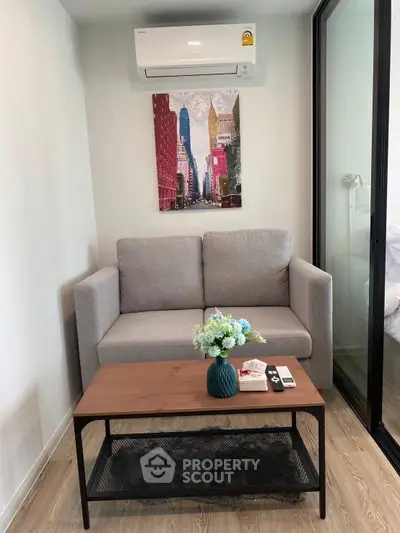 Cozy living room with modern sofa, air conditioning, and stylish decor in a compact apartment.