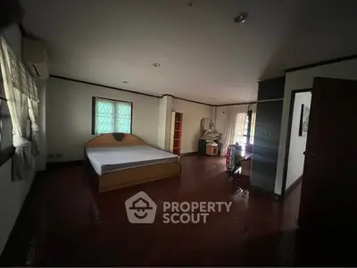 Spacious bedroom with wooden flooring and natural light