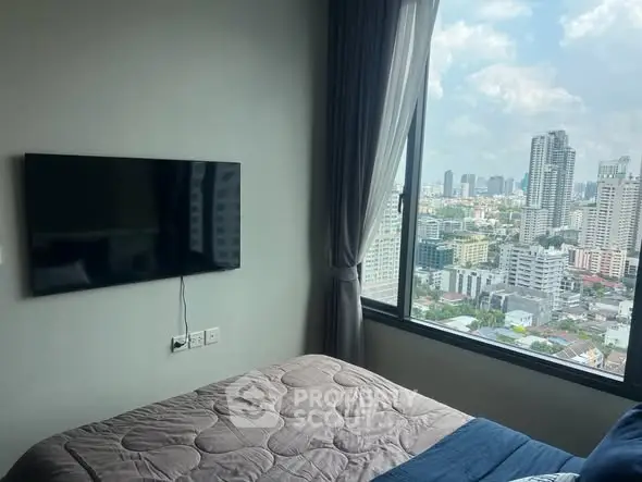 Modern bedroom with city view and wall-mounted TV in high-rise apartment.