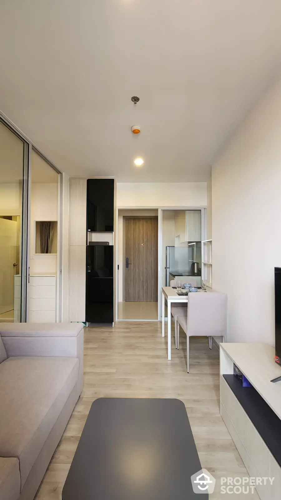 Modern minimalist living room seamlessly connected to a sleek kitchen, featuring elegant furnishings and a harmonious neutral color palette.