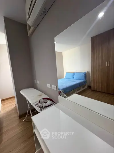 Modern bedroom with wooden flooring, mirrored dresser, and air conditioning unit.