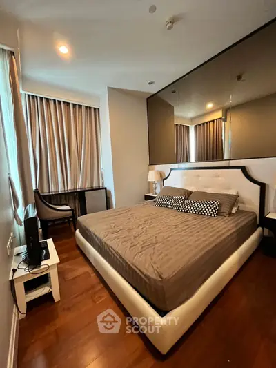 Luxurious bedroom with elegant decor and large mirror wall in modern apartment.
