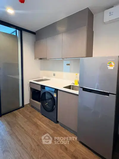 Modern kitchen with sleek cabinetry, built-in appliances, and wood flooring in a contemporary apartment.