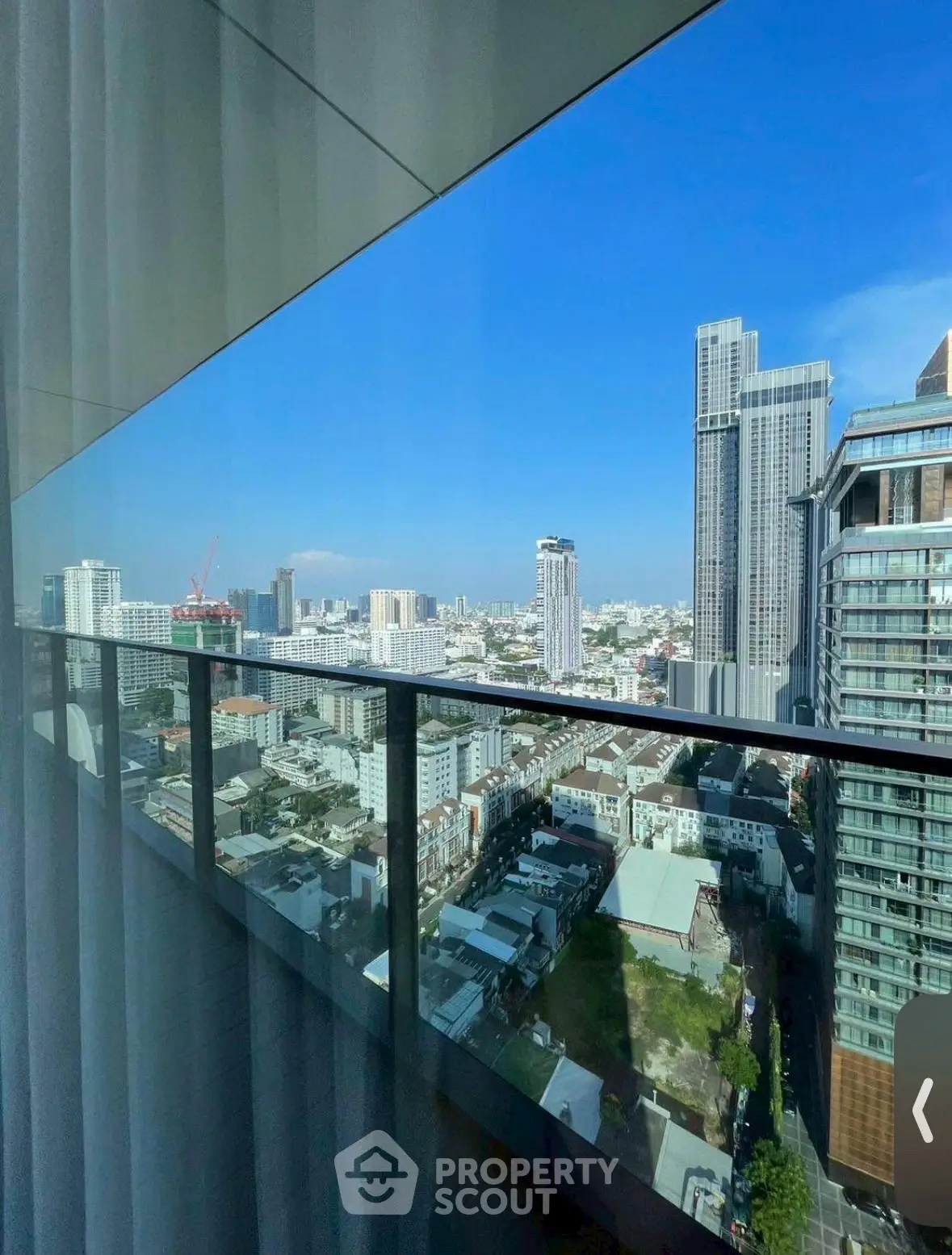 Stunning cityscape view from high-rise balcony with clear blue skies.