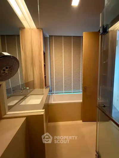Modern bathroom with sleek design and bathtub, featuring wooden accents and ambient lighting.