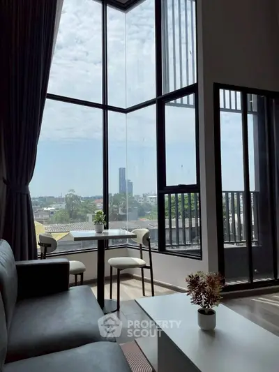 Modern living room with floor-to-ceiling windows offering stunning city views and elegant decor.