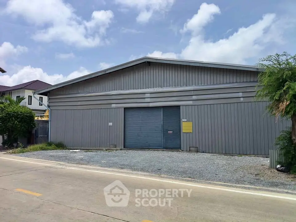 Spacious industrial warehouse with large metal doors and ample outdoor space, perfect for storage or business operations.