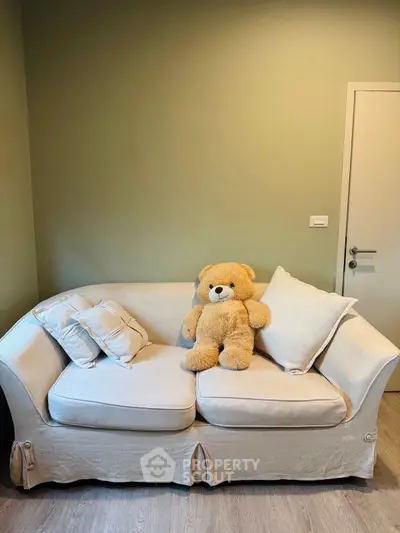 Cozy living room with a plush sofa and teddy bear, perfect for relaxation.