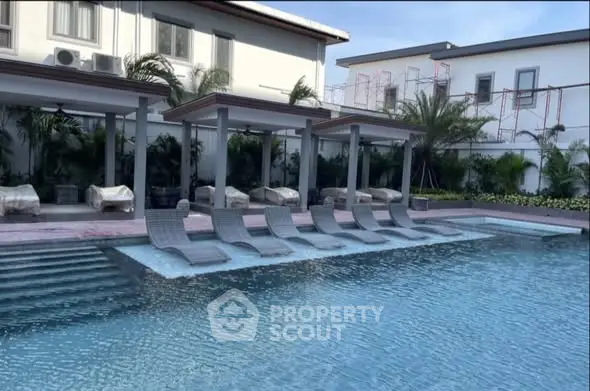 Luxurious poolside area with modern loungers and lush greenery in a high-end residential complex.