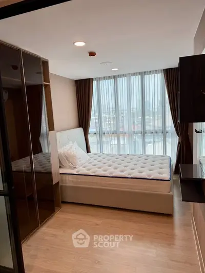 Modern bedroom with large windows and city view, featuring a comfortable bed and sleek wardrobe.