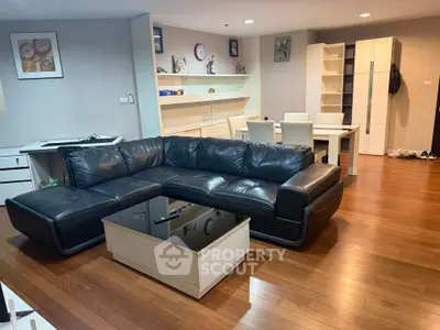 Spacious living room with modern black leather sofa and wooden flooring
