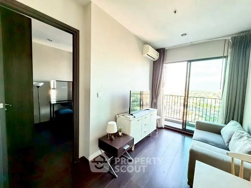 Modern living room with balcony view, featuring sleek furniture and natural light.