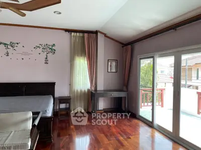 Spacious bedroom with wooden flooring and balcony access in a modern home