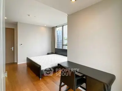 Modern bedroom with wooden flooring and sleek furniture in a high-rise apartment.