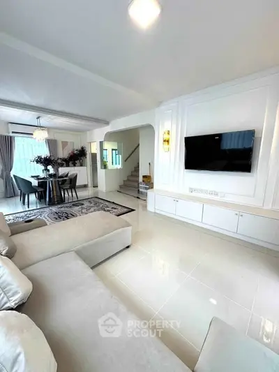 Spacious modern living room with elegant dining area and sleek TV setup.