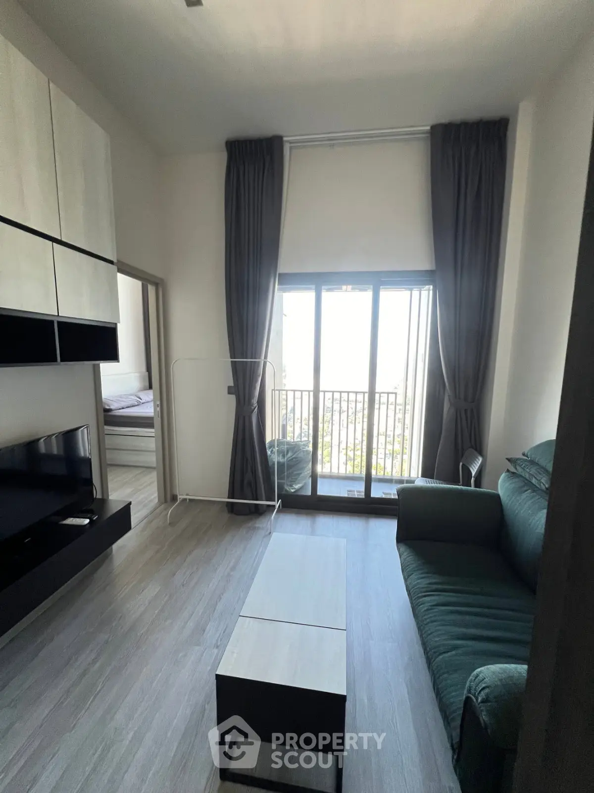 Modern living room with balcony view, featuring sleek furniture and floor-to-ceiling windows.