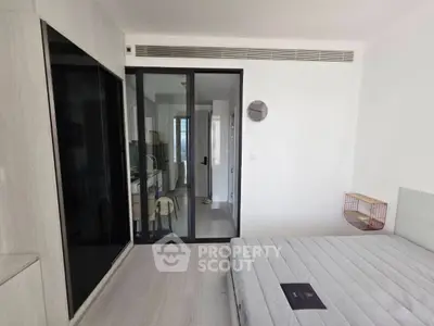 Modern bedroom with sleek design and glass sliding doors leading to a study area, featuring minimalist decor.