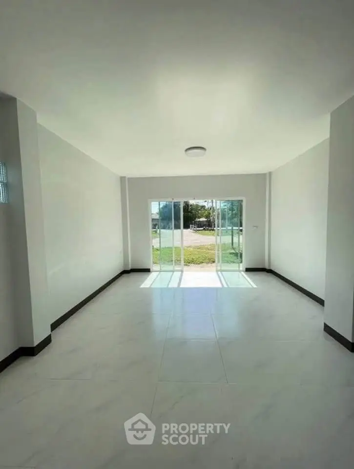 Spacious and bright living room with large windows and garden view, perfect for modern living.