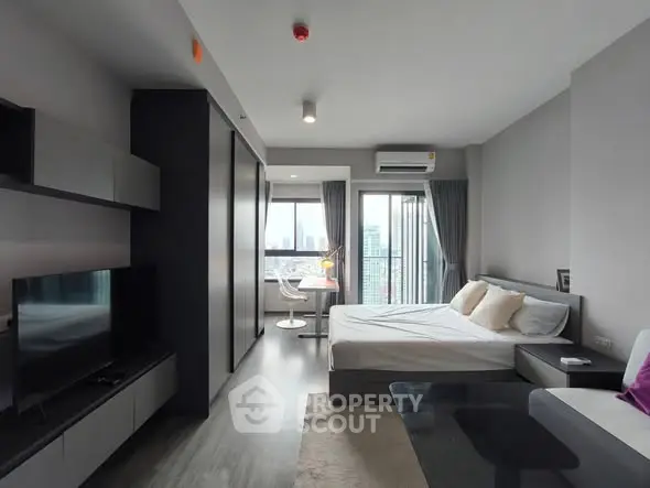 Modern studio apartment with city view, featuring sleek furniture and large windows.