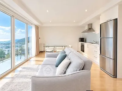 Luxurious open-plan living room with stunning sea view and modern kitchen in a bright, spacious apartment.