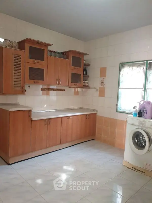 Spacious kitchen with wooden cabinets and washing machine