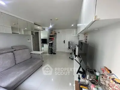 Modern living room with sleek furniture and mirrored wall in a compact apartment.