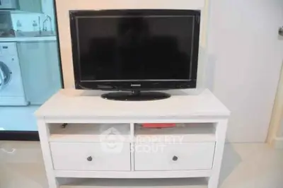 Modern living room with sleek TV stand and washing machine in view.