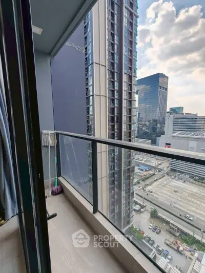 Modern high-rise balcony with cityscape view and glass railing.