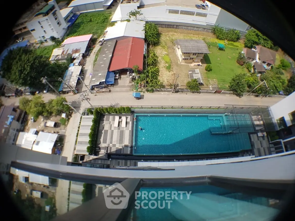 Stunning aerial view of modern apartment complex with luxurious swimming pool and lush greenery.