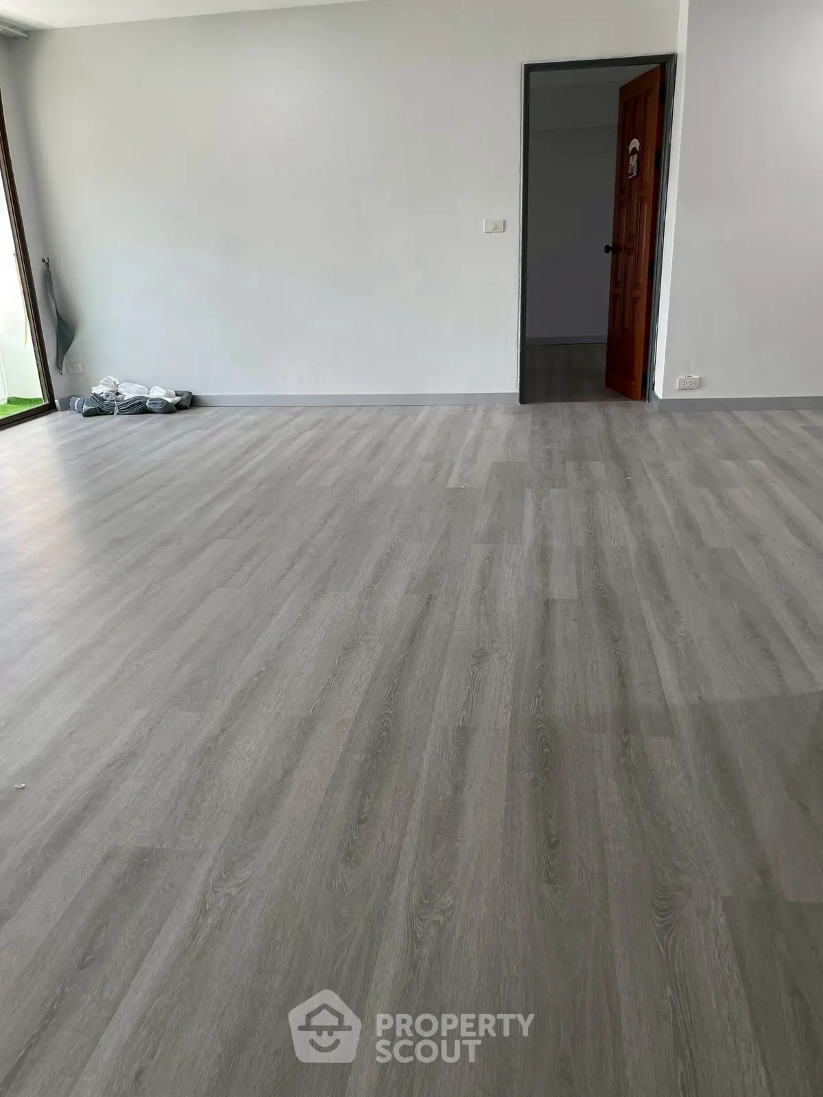 Spacious empty room with elegant wooden flooring and natural light.