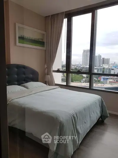 Modern bedroom with large windows offering stunning city views in a high-rise apartment.