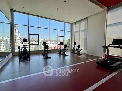 Modern gym with large windows and exercise equipment in a residential building.