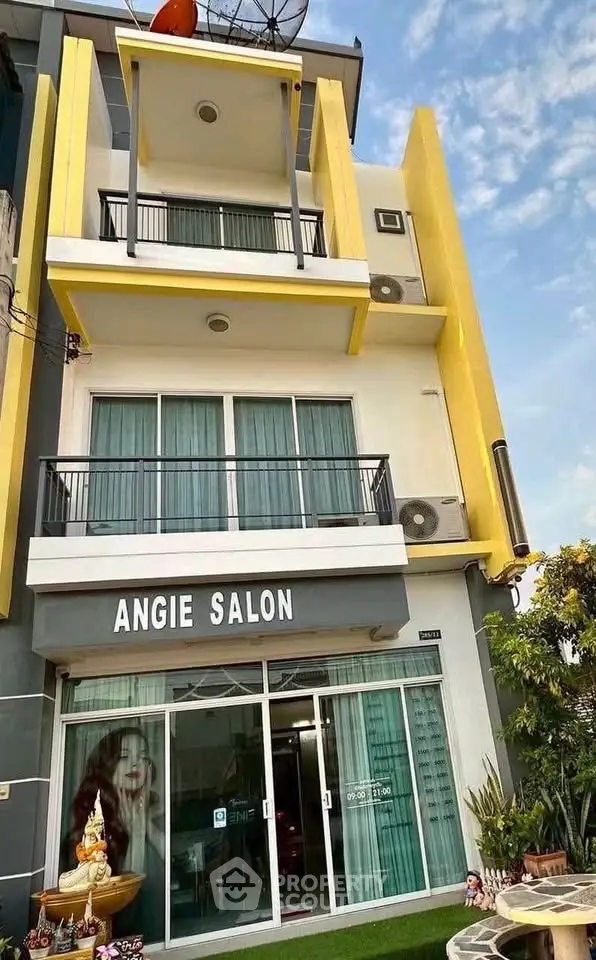 Modern three-story building with balconies and glass storefront, ideal for commercial use.