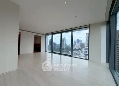 Spacious modern living room with panoramic city views and floor-to-ceiling windows.