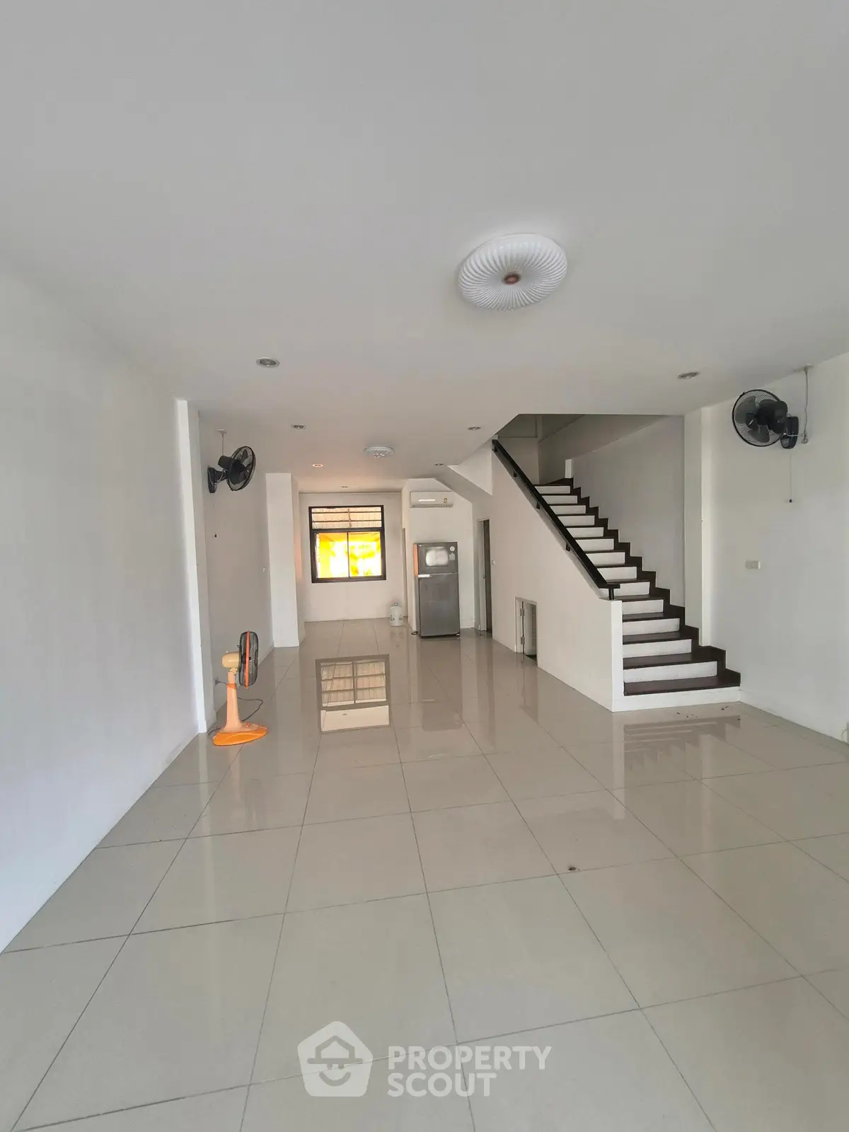 Spacious open-plan living area with modern staircase and tiled flooring