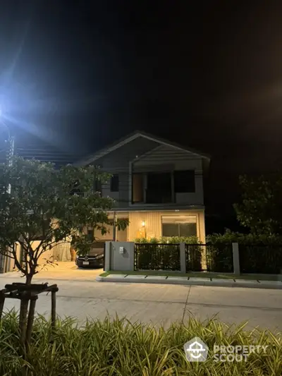 Modern two-story house with garage and garden at night, illuminated by streetlight.