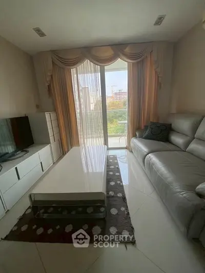 Elegant living room with modern furniture and large window offering natural light and garden view.