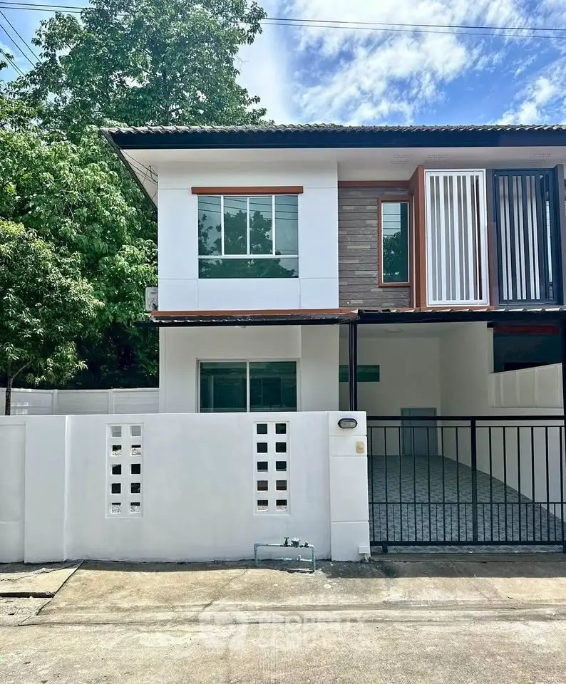 Modern two-story house with gated driveway and contemporary design in a serene neighborhood.
