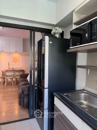 Modern kitchen with sleek appliances and cozy living area in open layout apartment.
