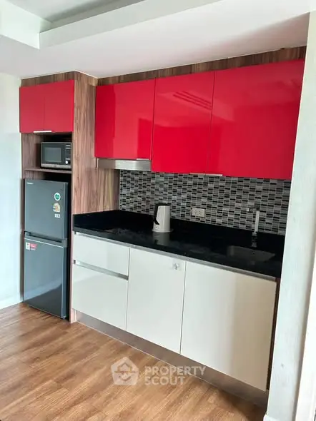 Modern kitchen with red cabinets and sleek appliances in a stylish apartment.