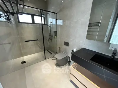Modern bathroom with sleek design, featuring a glass shower enclosure and stylish fixtures.