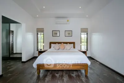 Spacious bedroom with elegant decor and large windows offering natural light.