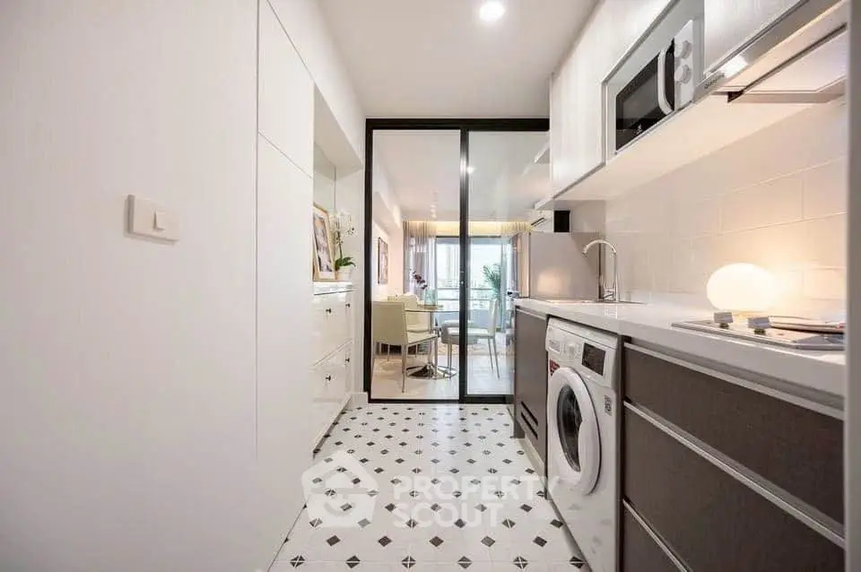 Modern kitchen with washing machine and open layout leading to dining area.