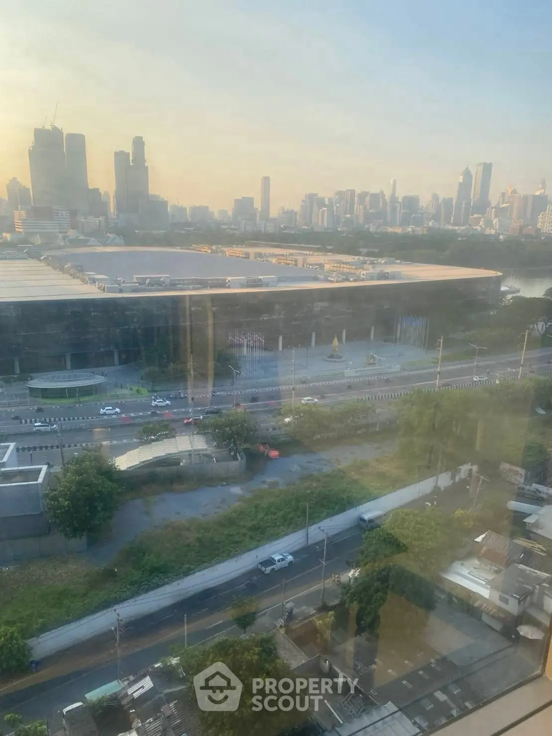 Stunning cityscape view from high-rise building window at sunset, showcasing urban skyline.