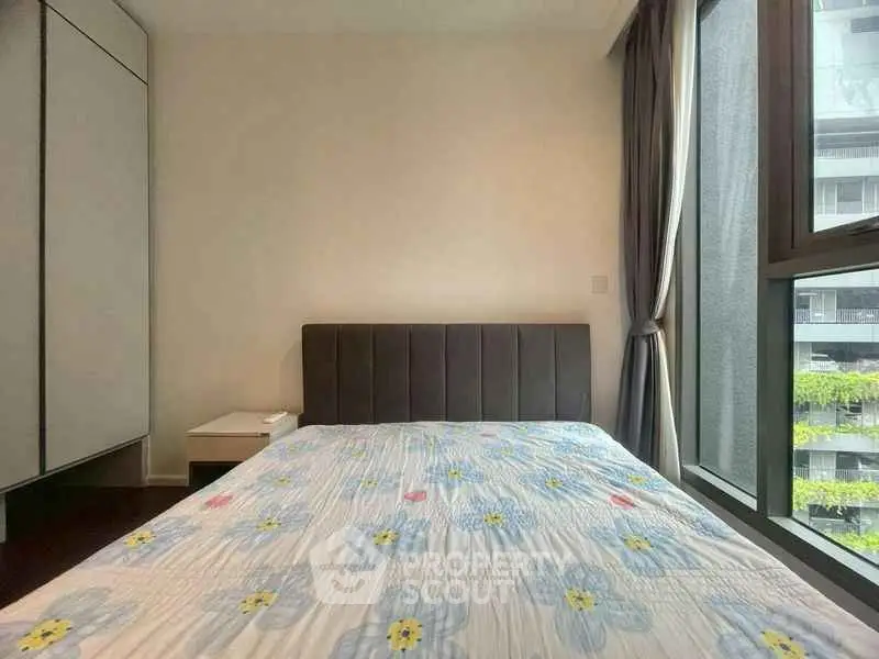 Cozy bedroom with large window and floral bedding in modern apartment