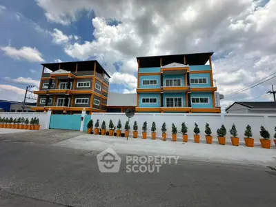 Modern colorful apartment buildings with vibrant facade and potted plants lining the entrance.
